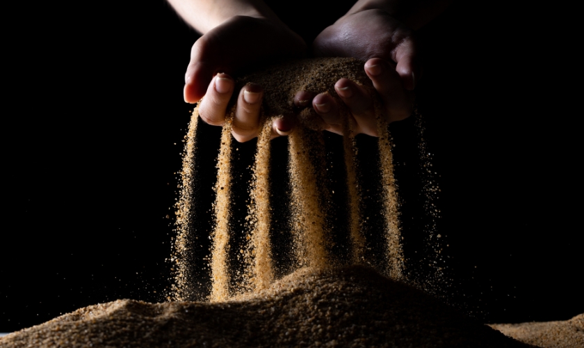 Sand rieselt durch zwei Hände